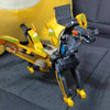 A black and yellow transforming dinosaur car toy is shown resting on a dark gray fabric surface.
