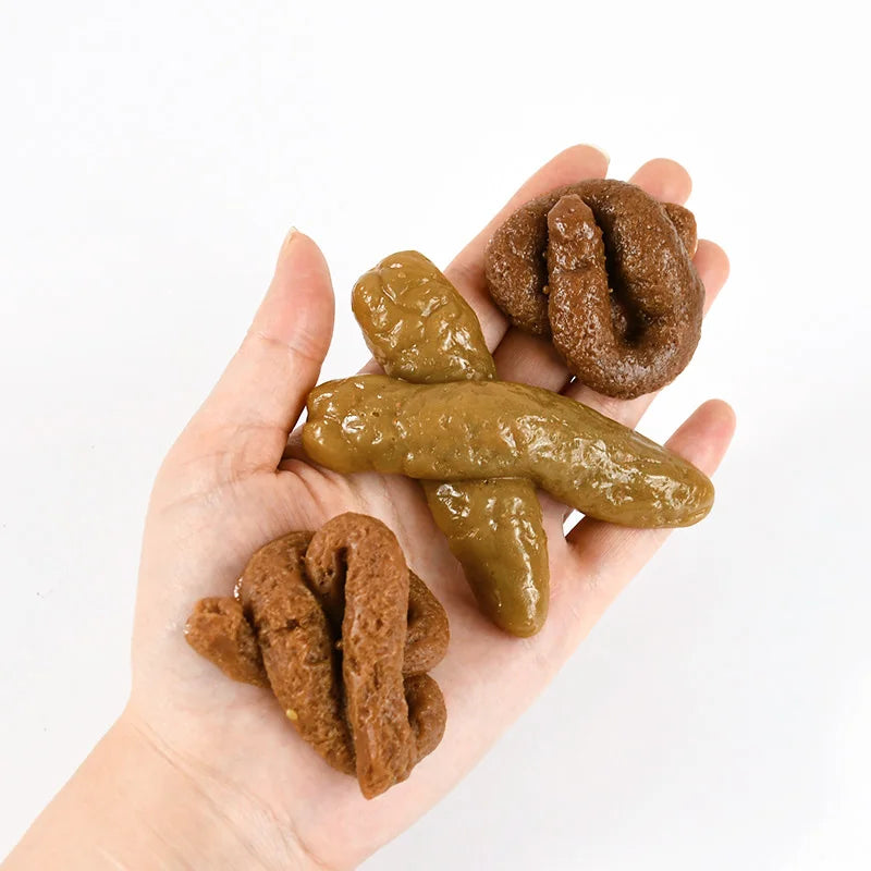 A hand holds several realistic squishy prank toys shaped like soft fake poop in various shades of brown.