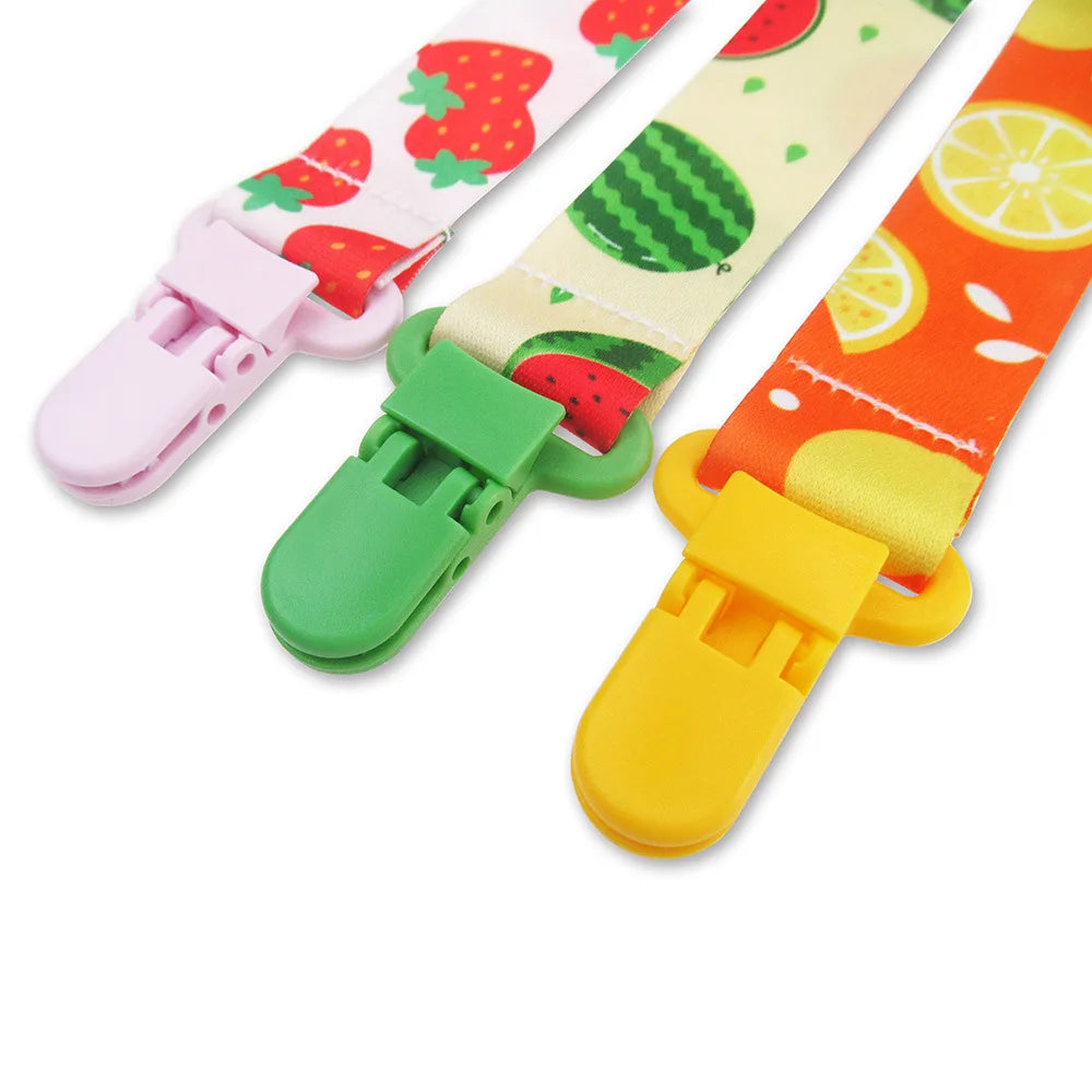 Ein Set personalisierter Cartoon-Milchflaschenclips in rosa, grün und gelben Farben.