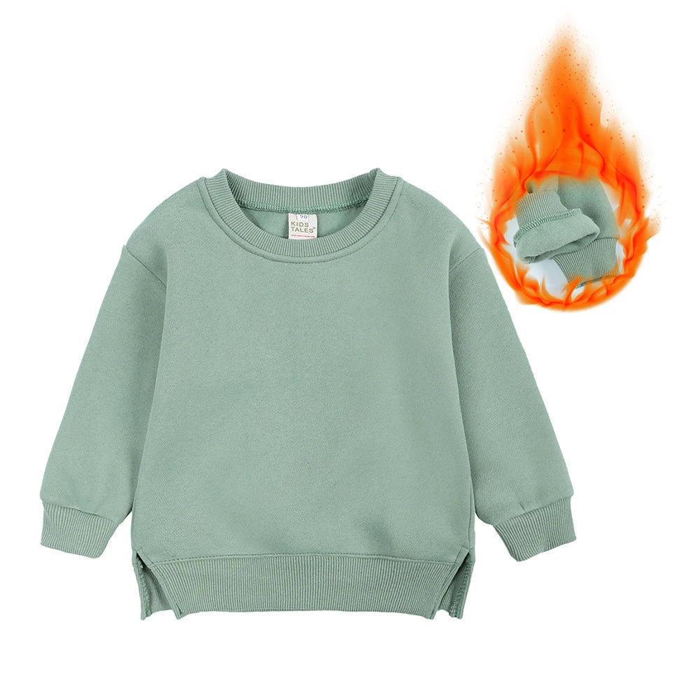 A light sage green kids pullover hoodie with a small tag and an orange flame graphic.