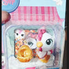 A clear plastic package containing three small white and pink animal figures for sale.
