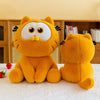 Two orange Garfield plush dolls, one large and one small, sitting on a white surface.