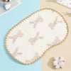 A cream-colored, embroidered flat pillow with a scalloped edge and a light pink bunny pattern on a pale blue background.