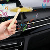 A hand is using a clip-on mini alloy cymbal ornament to decorate a car air vent.