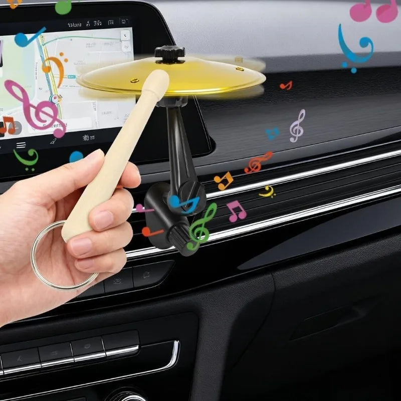A hand is using a clip-on mini alloy cymbal ornament to decorate a car air vent.