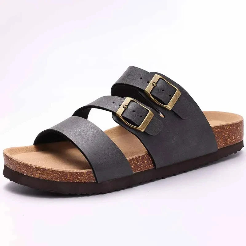 A pair of black suede cork mules with gold-toned buckles and arch support.