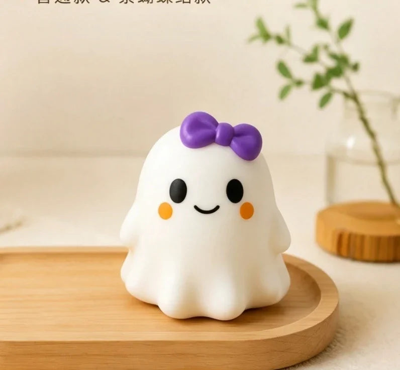 A white squishy ghost stress ball with a purple bow resting on a wooden surface.