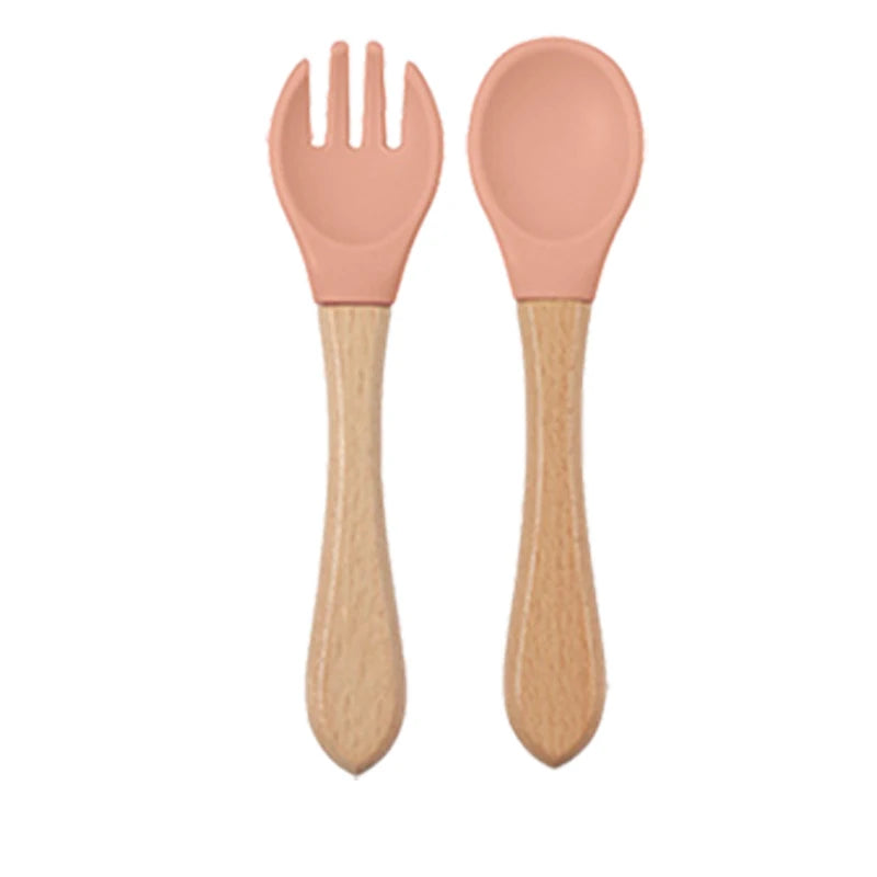 Ensemble d'alimentation en silicone pour tout-petits avec fourchette et cuillère roses à manches en bois.