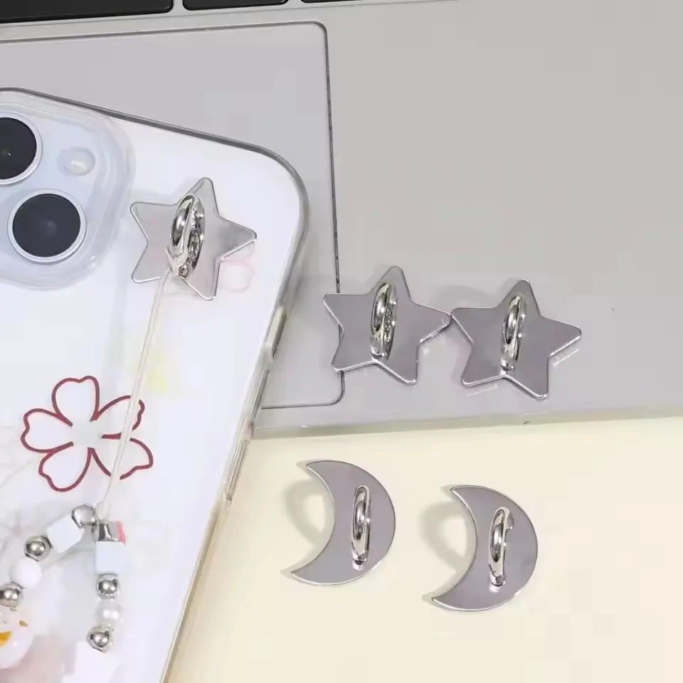 Silver star-shaped phone charm hooks with adhesive backing displayed on a laptop surface.