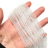 A hand holds a strand of clear faceted natural stone beads for DIY jewelry making