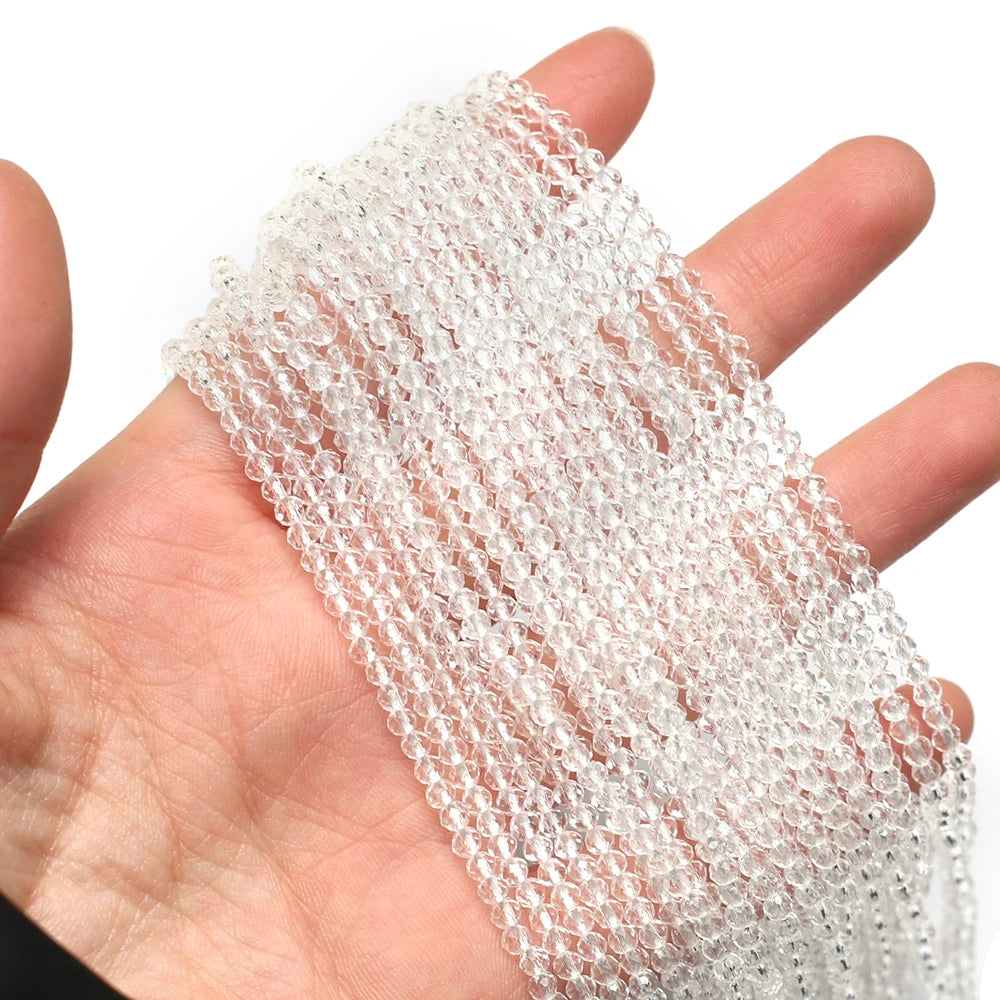 A hand holds a strand of clear faceted natural stone beads for DIY jewelry making
