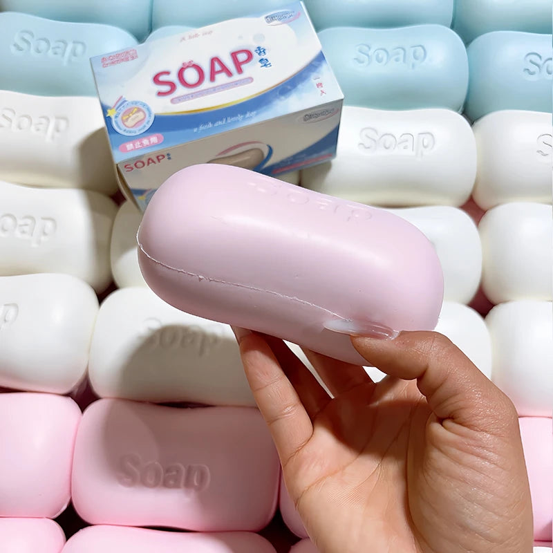 A hand holds a pink soap ball squishy fidget toy next to a box of soap.