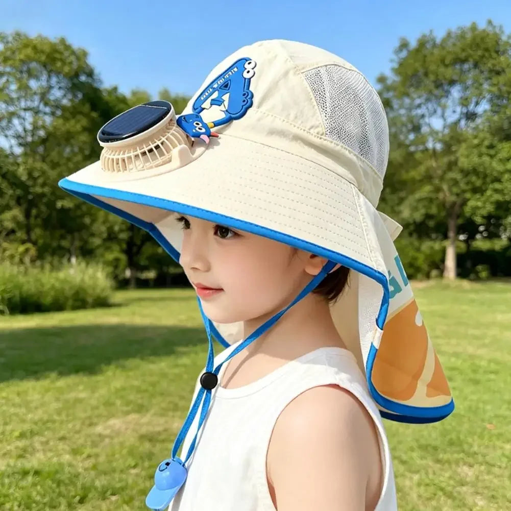 A young girl wearing a beige sun hat with a blue and white design and a USB charging fan attached, outdoors.