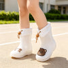 A pair of white kids' waterproof bear rain boots with anti-slip soles standing on a paved surface.