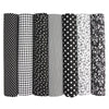 A pack of seven rolls of cotton fabric squares for quilting and patchwork featuring various black, white, and striped pattern
