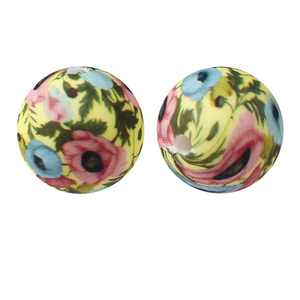 Pair of round silicone beads with floral patterns in yellow, pink, and blue tones