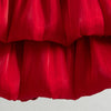 A close-up of a vibrant red pleated dress for a baby girl, showing the fabric texture and folds.
