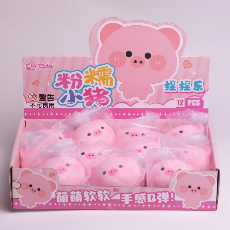 A box of pink pig squishy stress relief toys with cute face designs.