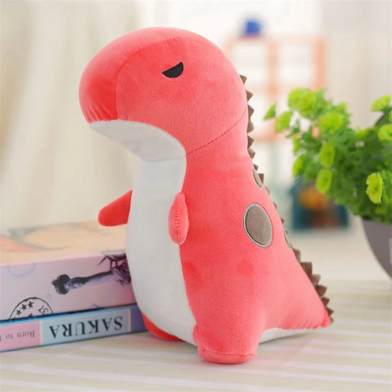 A soft pink and white triceratops plush dinosaur toy lying on a white surface.