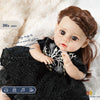 A lifelike 14-inch reborn baby doll with a dark outfit and hair, shown in a close-up.