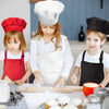 Two children wearing chef aprons and hats are preparing food on a kitchen counter.