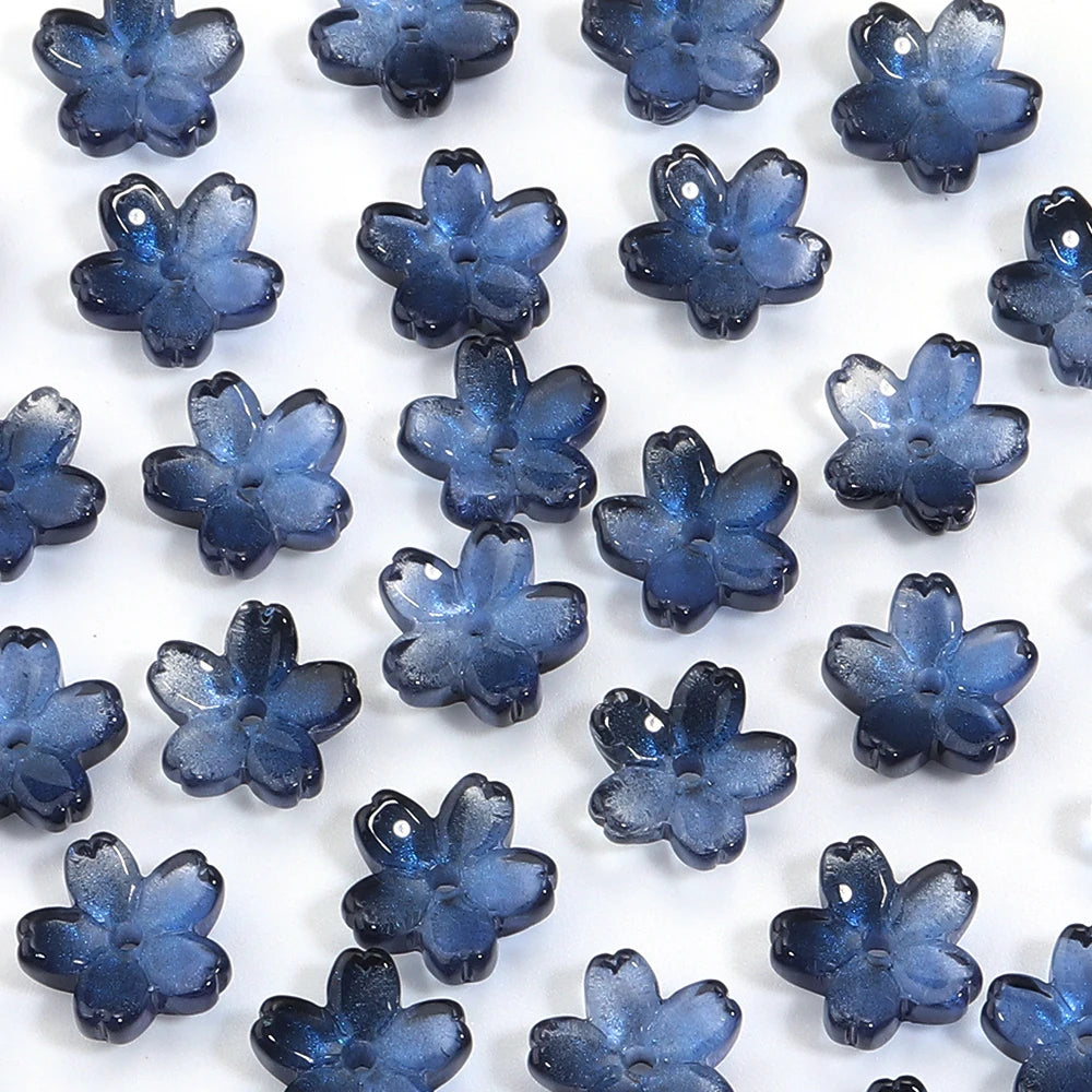 A collection of 50 small, blue glass beads shaped like cherry blossom flowers for jewelry making