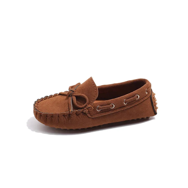 A brown girls' slip-on moccasin shoe with a bow detail and leather laces.