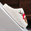 A white plush non-slip indoor slipper with a reindeer design is shown resting on a white surface.