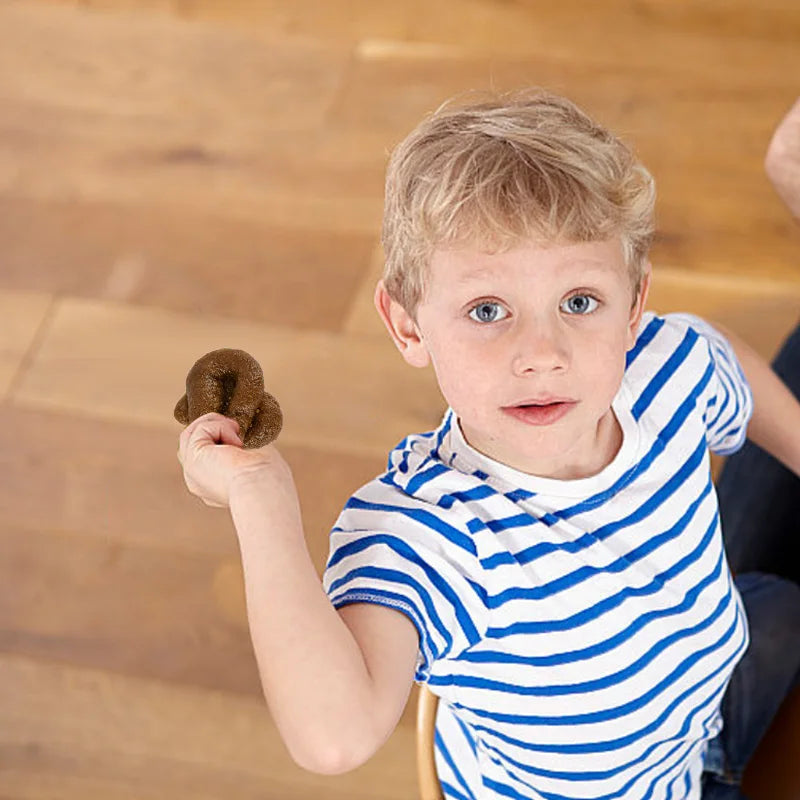 Un jeune garçon tient un jouet de caca brun et réaliste dans sa main.
