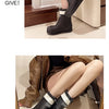 A pair of black waterproof mid-calf rain boots with white trim and non-slip soles shown on a person's leg.