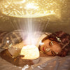 A woman is relaxing under a glowing night light projector that casts starry sky and galaxy effects onto her face.