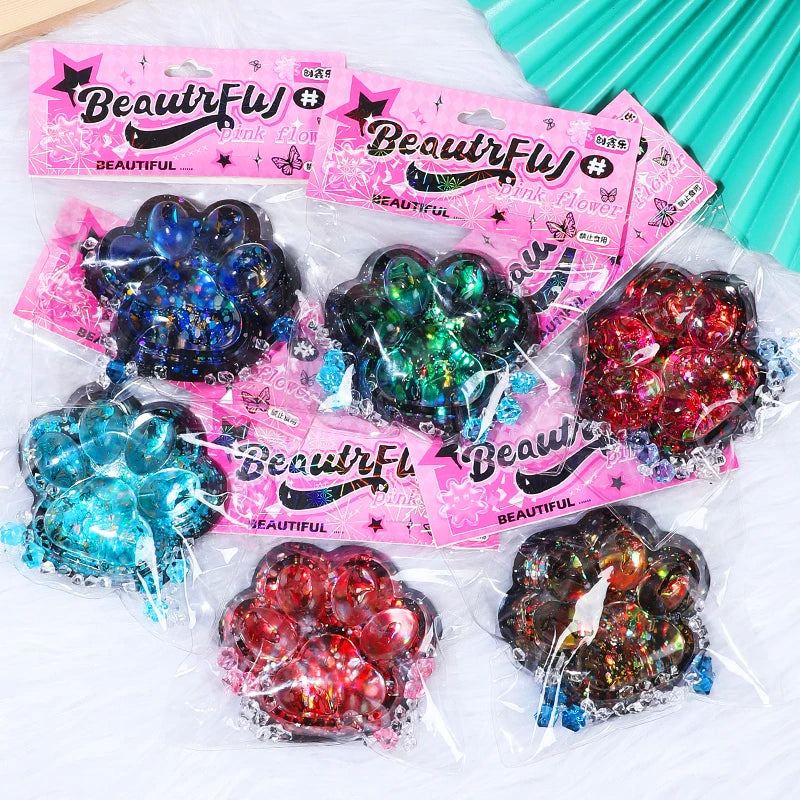 A collection of pink and iridescent squishy fidget toys shaped like cat paws for stress relief and sensory play