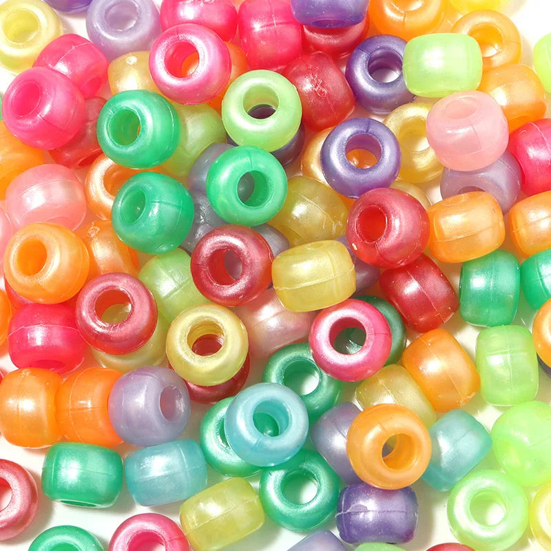 A pile of colorful rainbow pony beads in various shades including pink, purple, green, and orange.