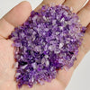 A hand holds a pile of purple amethyst stone chips for jewelry making and home decor