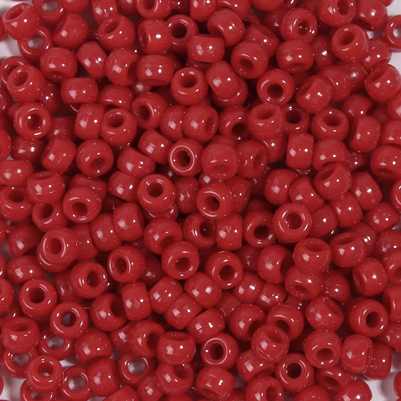 A close-up view of a 100-pack of small, round, red pony beads for jewelry making and craft projects.