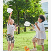 Two children playing outdoors, throwing and catching a white flying disc toy.
