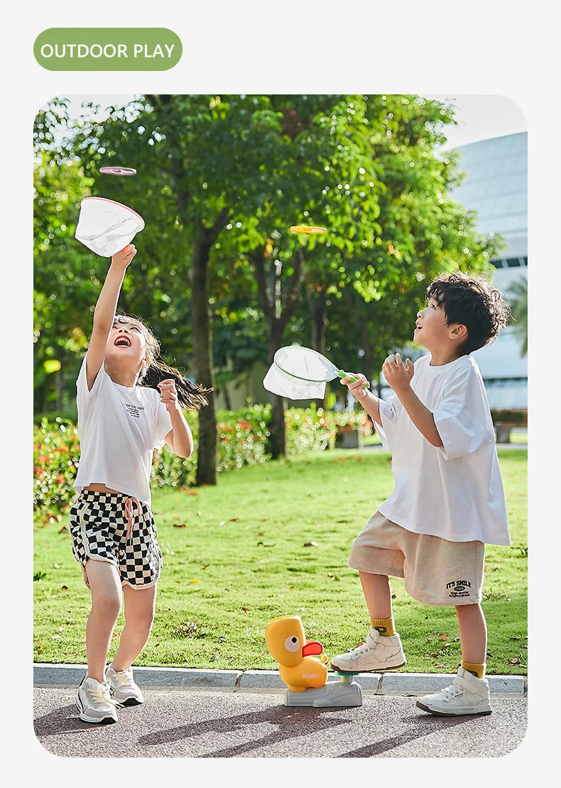Two children playing outdoors, throwing and catching a white flying disc toy.