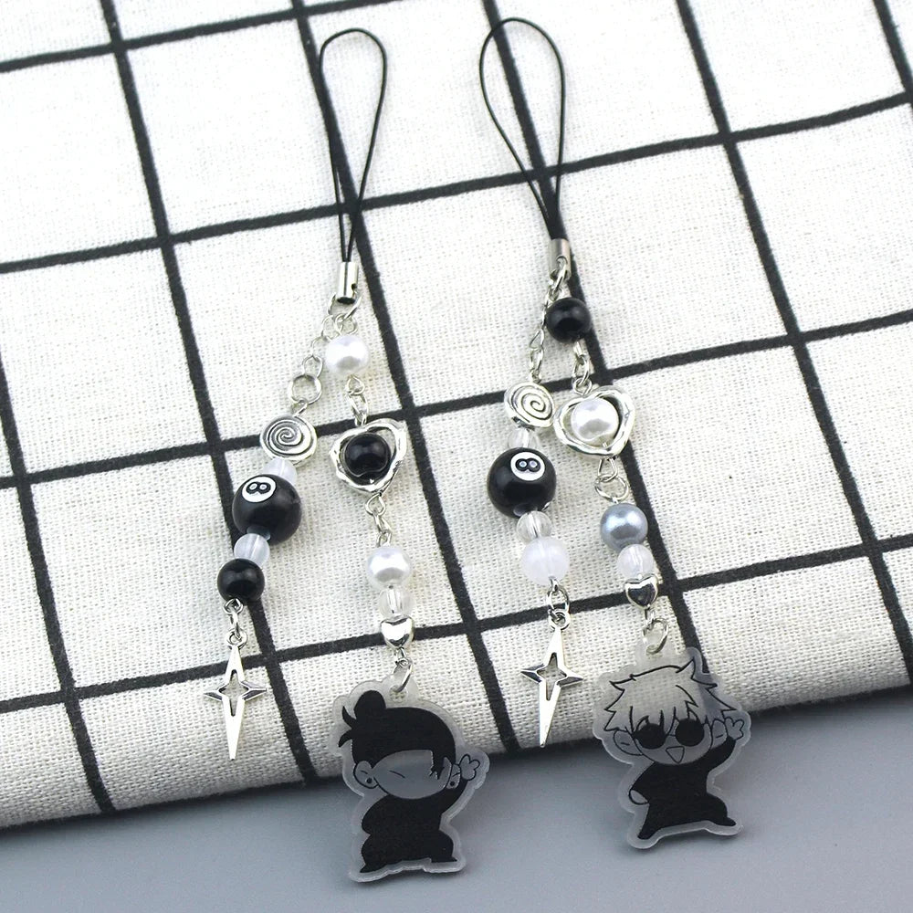 Anime-inspired keychain featuring black and white charms on a checkered fabric background