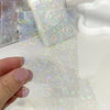 A hand holds a pack of holographic card sleeves featuring multicolored heart designs for trading cards.