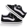 A pair of black and white striped canvas baby sneakers shown from the side.