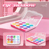 A pink and purple eyeshadow palette with various colored shades is displayed on a pink surface.