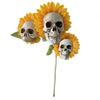 A sunflower with a skull decoration on a garden stake.
