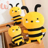 Three yellow and black bee plush toys sitting on a wooden surface.