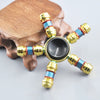 A metal fidget spinner with a rainbow finish rests on a brown bone.