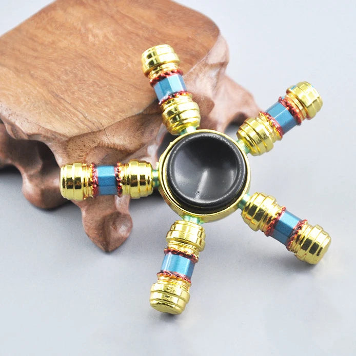 A metal fidget spinner with a rainbow finish rests on a brown bone.