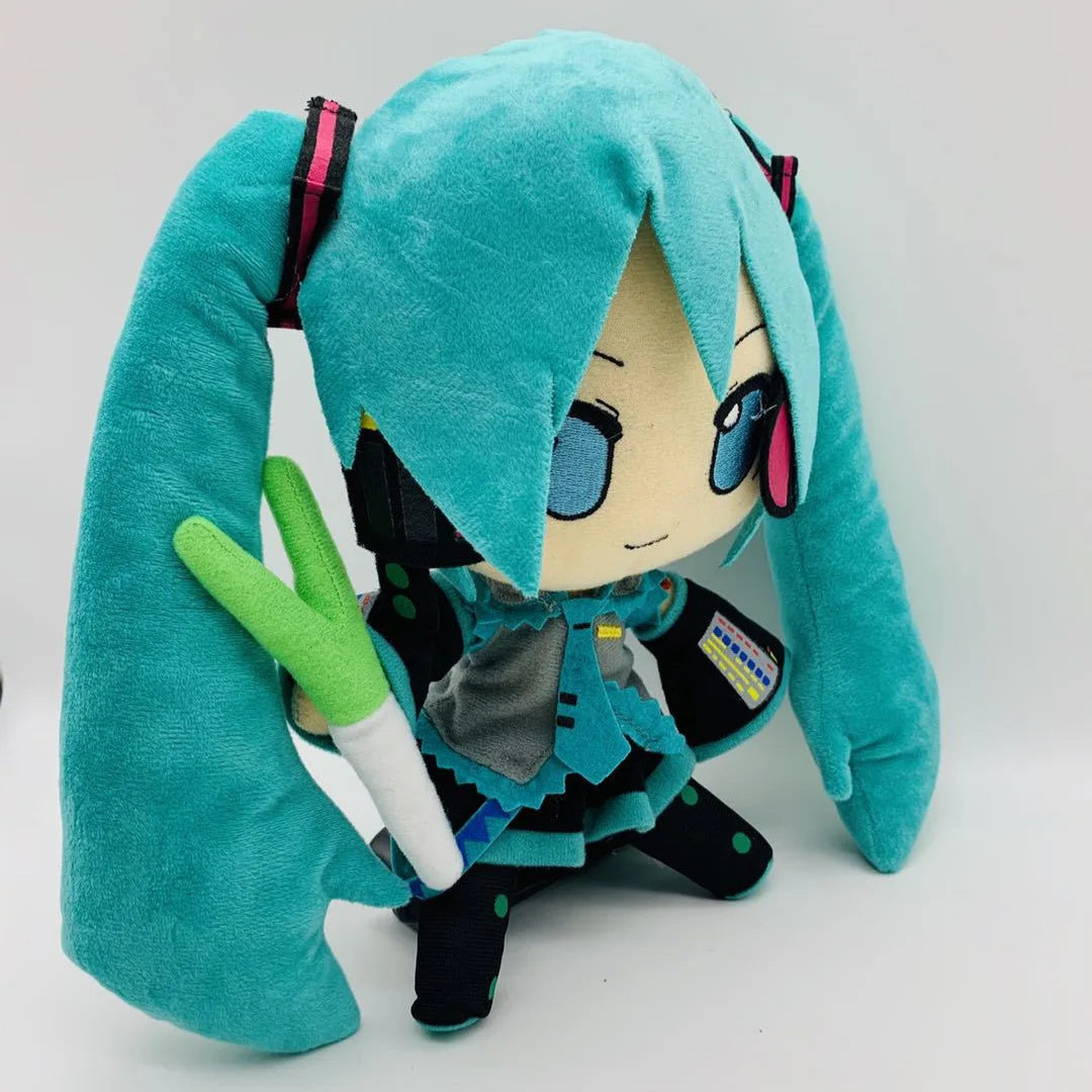 A teal plush doll of Hatsune Miku with long hair and black outfit holding a white pencil.