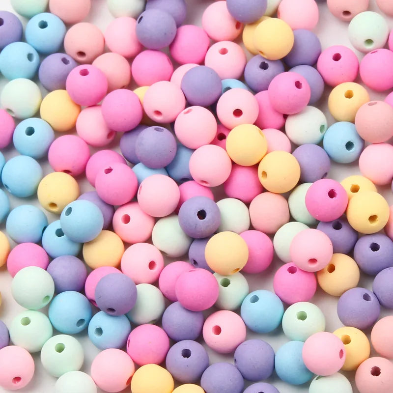 A close-up view of various colored matte acrylic beads used for jewelry making.