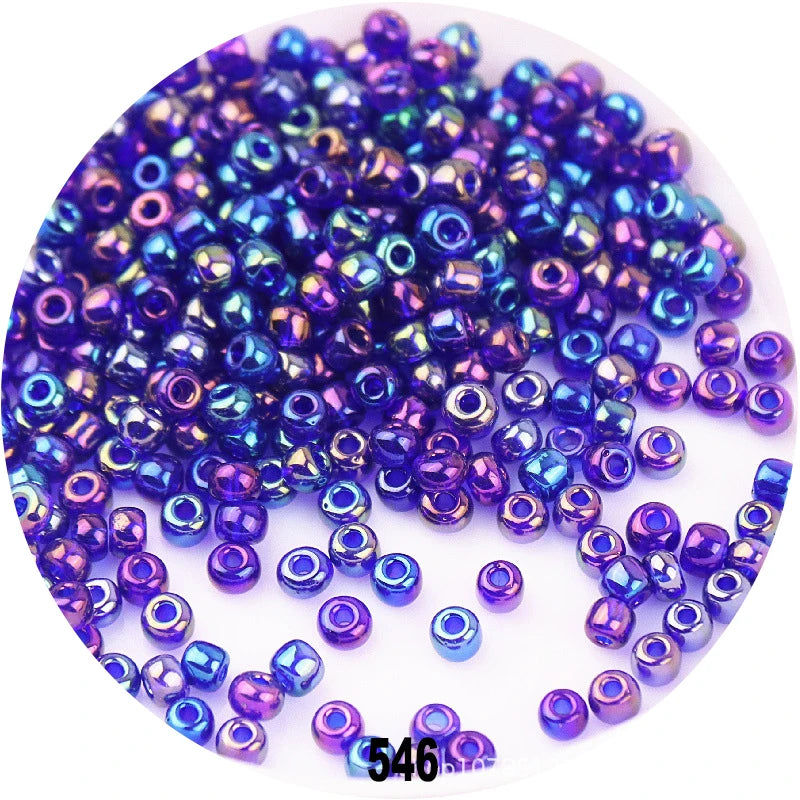 A pile of colorful round loose glass seed beads in various shades of blue and purple for jewelry making