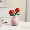 A pink vase holds a vibrant red rose flower, part of a floral bouquet building block set.