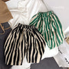 A pair of black and beige striped cotton harem pants for kids lying on a white surface.